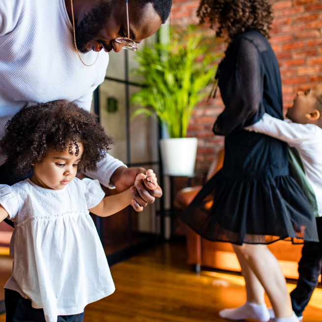 Black family dancing around. Mother and father dancing with young daughter and son