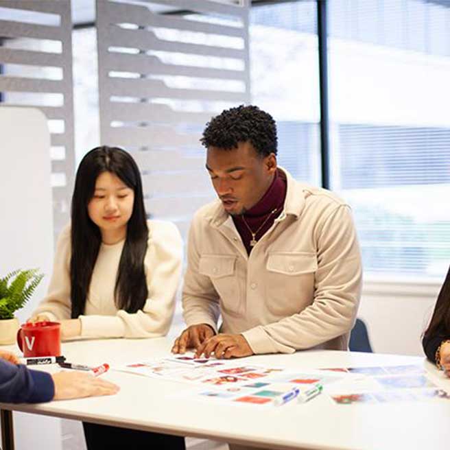Colleagues standing at a table, working together on printed marketing collateral. 